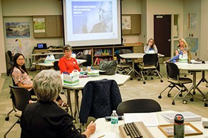 A photo taken during Project SERVE's mentor kickoff where mentors converse with each other and watch a powerpoint.